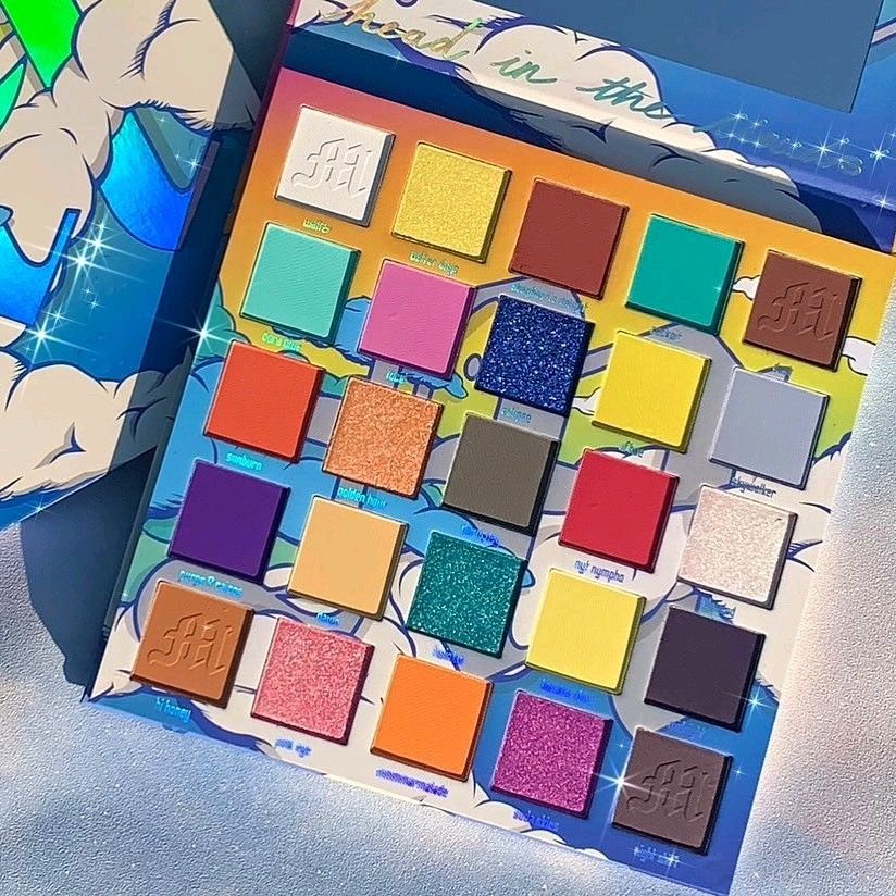 Colorful makeup palette with many bright square eyeshadow pans on a blue background