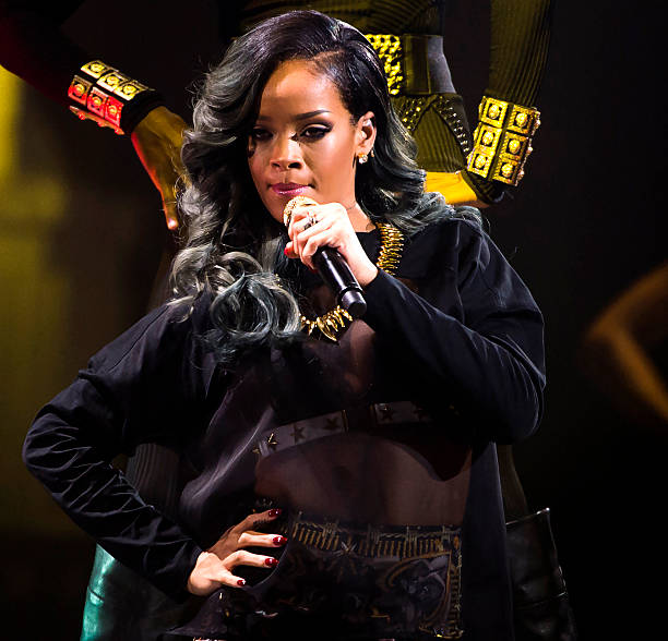 Singer performing on stage with microphone in black outfit under stage lights
