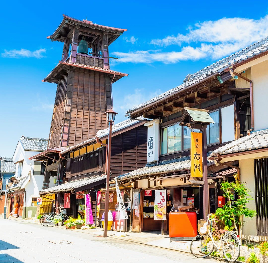 Historic Japanese street in Kawagoe with traditional wooden buildings and bell tower under blue sky