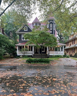 Victorian house with turret and porch surrounded by trees and autumn leaves