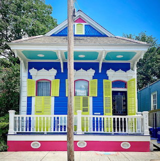 Victorian house painted in vibrant blue, yellow, pink and green with white porch and colorful gabled roof