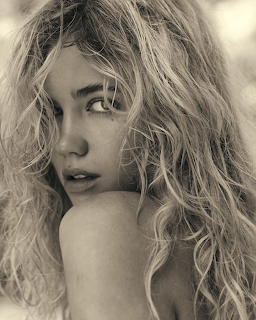Close-up sepia portrait of a woman with long curly hair looking over her shoulder