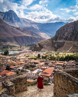 Person overlooking Ollantaytambo village with Incan terraces and Andes mountains in Peru