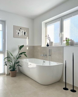 Modern bathroom with freestanding white bathtub, green plants, and minimalist decor