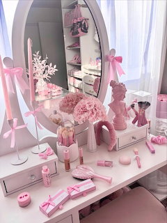 White vanity desk with oval mirror decorated with pink ribbons, bows, flowers, and beauty accessories