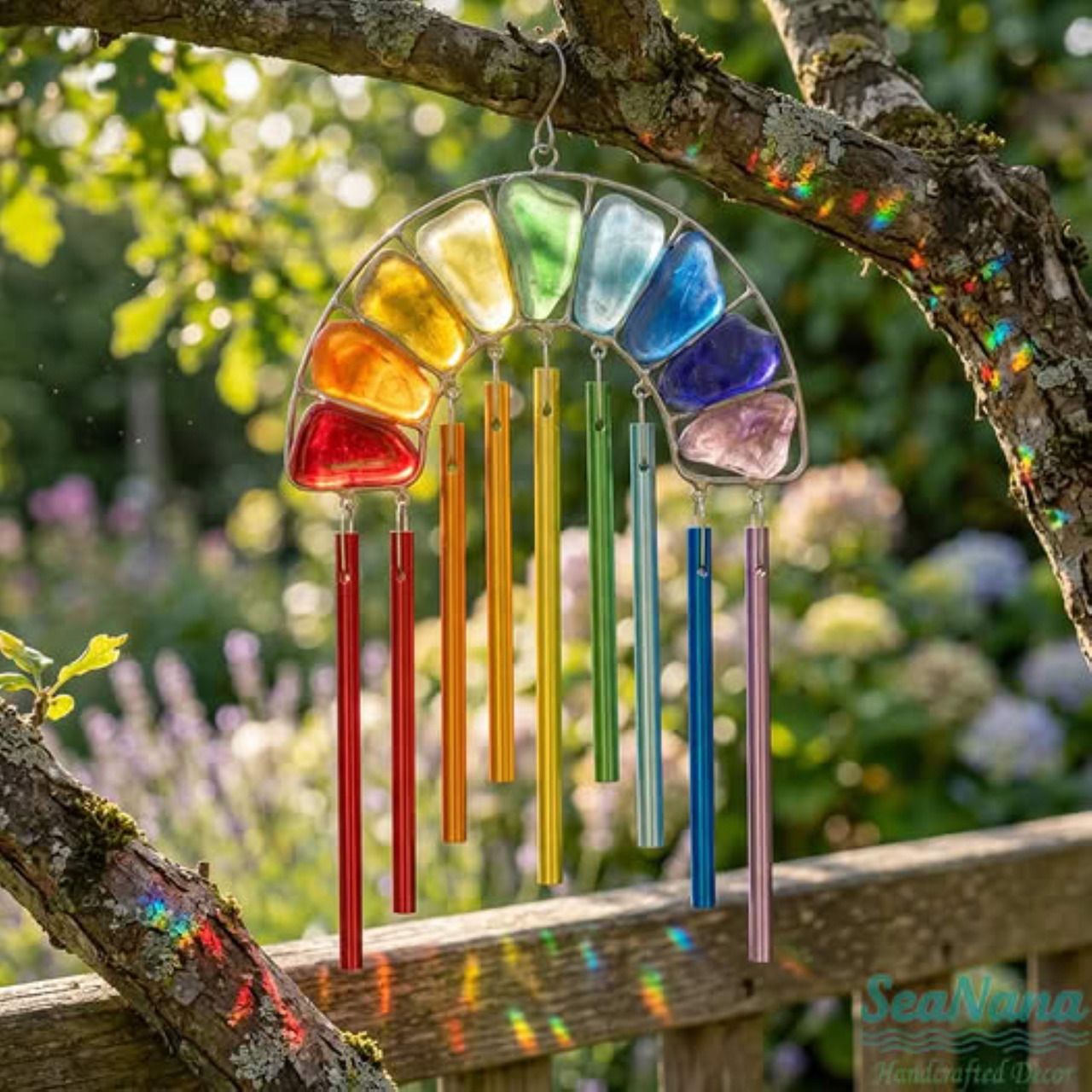 Colorful rainbow windchimes with glass ornaments hanging from tree branch outdoors