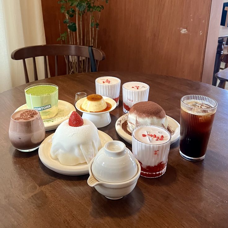 Desserts and coffee drinks on a wooden table, including mochi soufflés, parfaits, and iced coffee