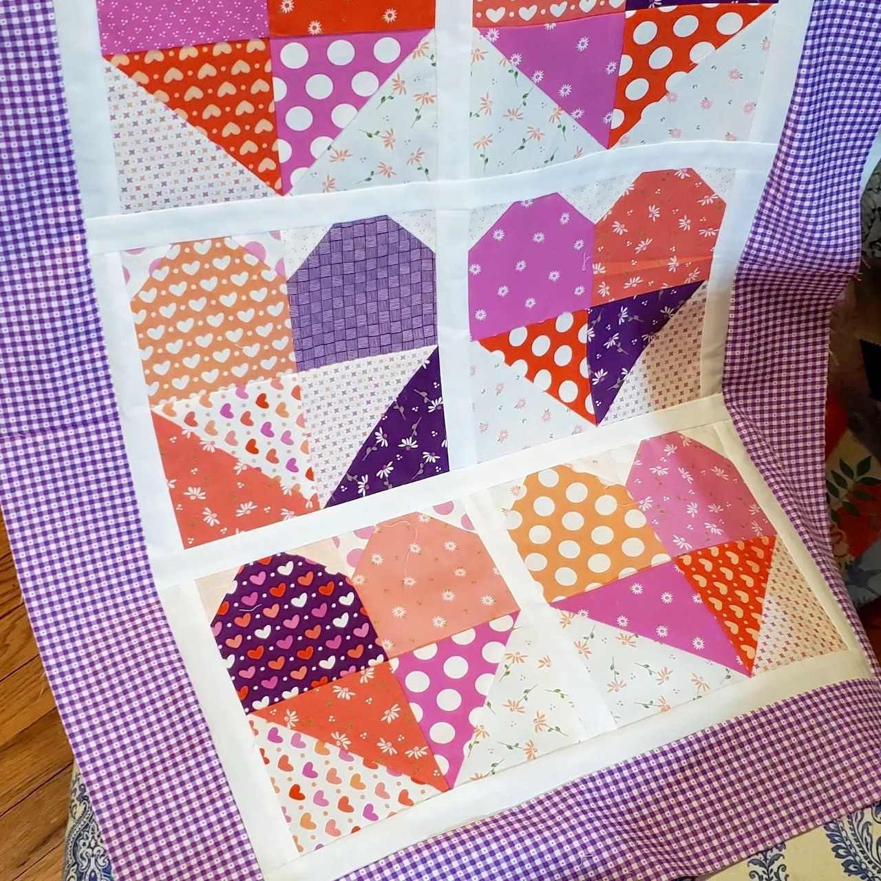 Colorful patchwork quilt with heart designs in pink, purple, orange and red polka dot fabrics