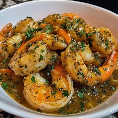 Bowl of garlic butter shrimp garnished with fresh parsley in golden sauce