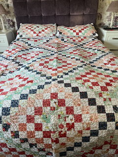 Patchwork quilt with multicolored checkered squares on bed with matching pillows