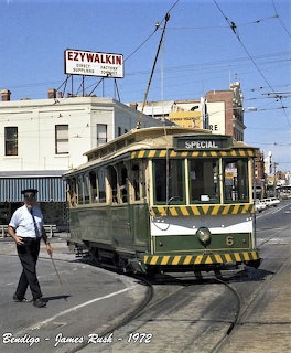 Vintage green and cream tram number 6 on a Bendigo street with a man walking nearby