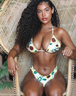 Woman with long curly black hair in sunflower bikini seated on wicker chair