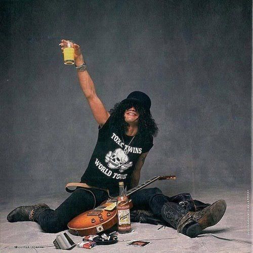 Rock musician in top hat sitting with electric guitar and bottle