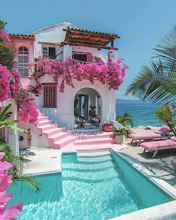Pink stucco villa with flowering bougainvillea, turquoise pool, pink steps, palm trees, and ocean view