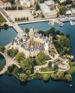 Aerial view of ornate Schwerin Castle on island surrounded by water with boats and bridges