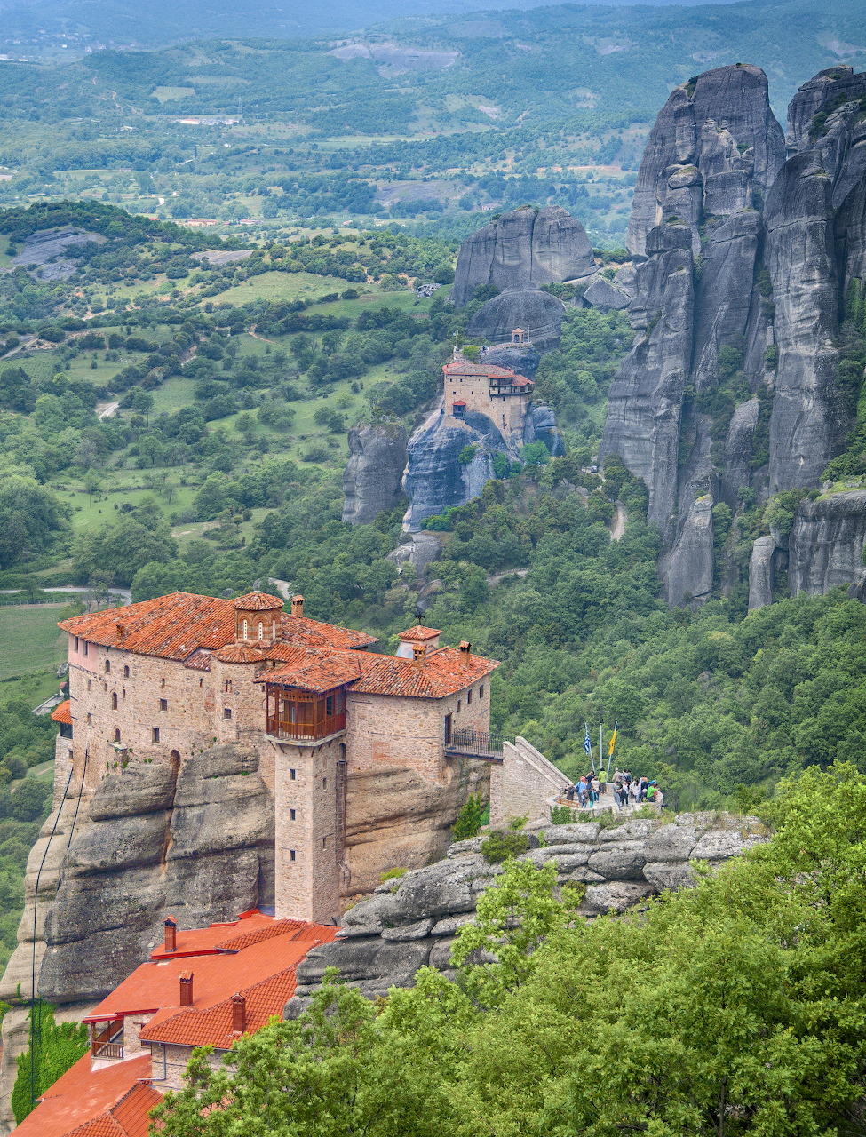 Rousanou Monastery atop a steep rock pillar in Meteora with massive sandstone cliffs and green landscape