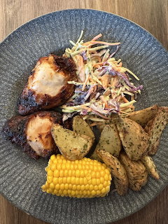 Overhead view of grilled chicken dinner with corn, potatoes and coleslaw on blue plate