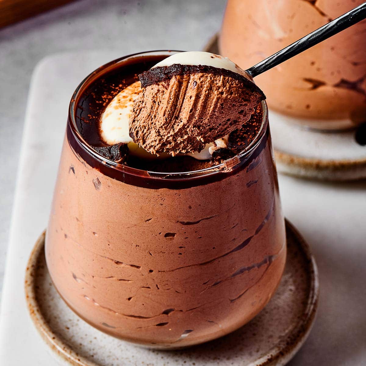 Chocolate mousse in glass with spoon, garnished with coffee beans and macarons