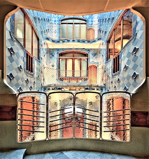 Interior balcony view into Casa Batlló lightwell with curved railings, windows, and blue tiled walls