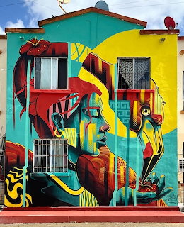 Colorful street art mural on a building with two stylized faces and abstract shapes