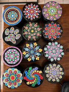 Colorful round decorative boxes with detailed floral and mandala patterns on a wooden table