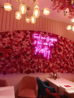 Cafe interior with pink rose flower wall, neon sign, and modern globe pendant lights
