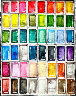 Overhead view of a watercolor paint palette with colorful paint wells arranged in rows