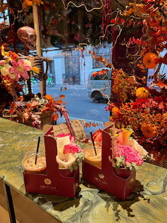Two iced drinks in red carriers on a table with flowers and autumn cafe decor by a window