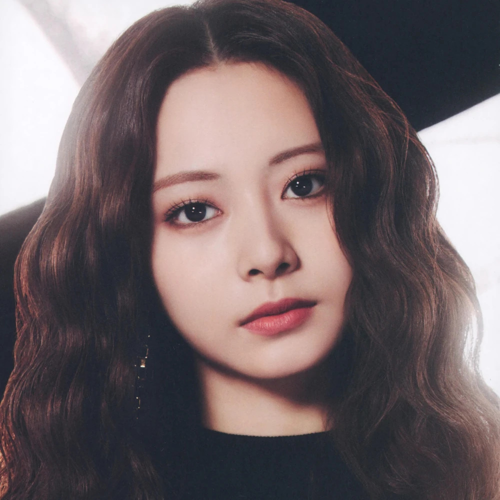 Close-up portrait of Tzuyu with long wavy brown hair and a dark top