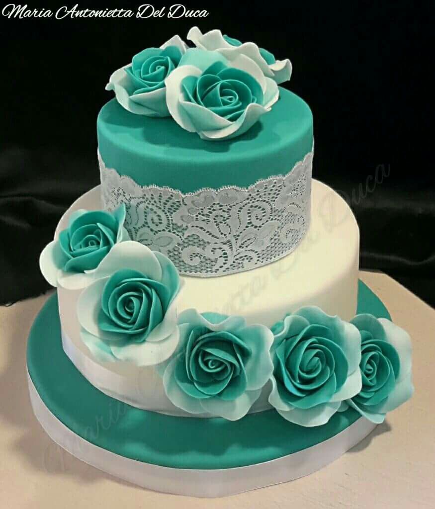 Two-tier white and teal cake with sugar roses and lace icing