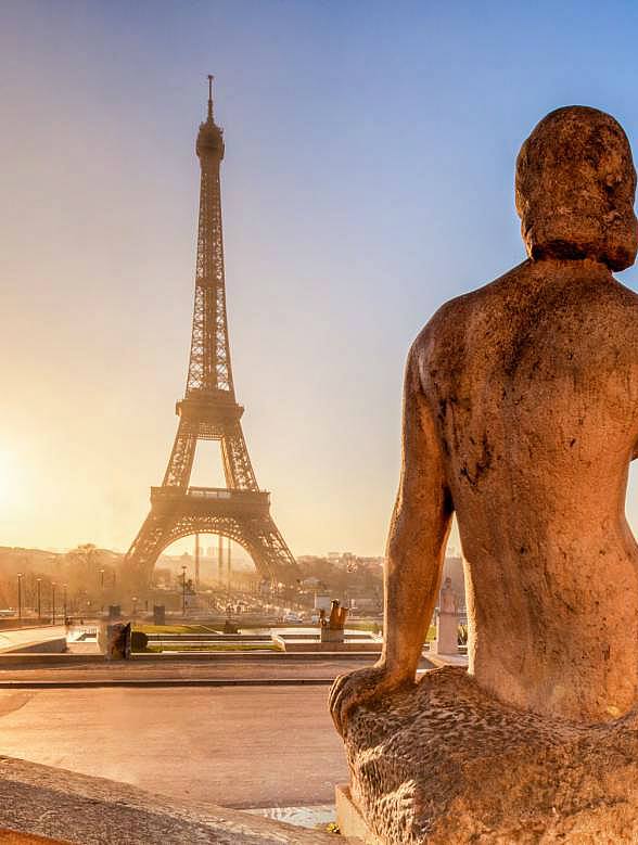 Stone statue at Trocadéro with the Eiffel Tower in the background at sunrise, Paris