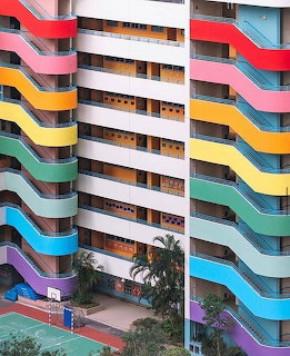 Modern building with horizontal rainbow-colored wavy balconies creating a striped pattern across the facade