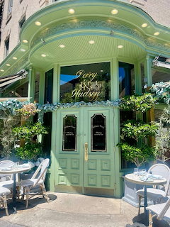 Green ornate cafe entrance with plants and outdoor seating in New York City