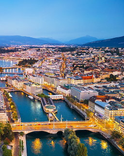 Aerial dusk view of Geneva Switzerland with the Rhône river, bridges, and illuminated cityscape