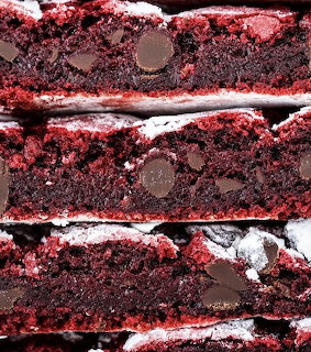 Stacked red velvet crinkle cookies with chocolate chips and powdered sugar coating