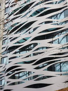 Modern building facade with white wavy panels over blue glass windows