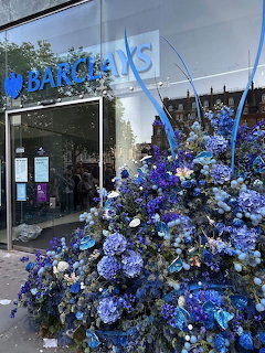 Barclays storefront with a large blue and purple flower display outside