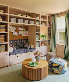 Children's room with built-in bookshelf reading nook, round wooden coffee table, and colorful fabric ottoman