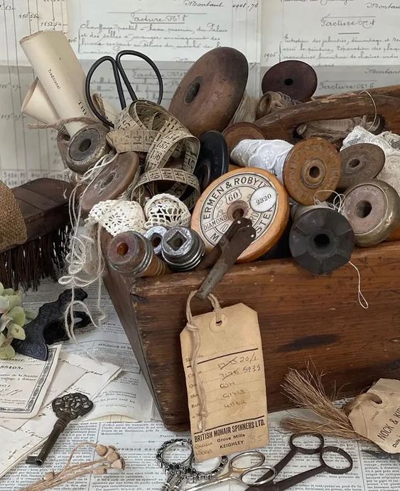 Assortment of vintage wooden thread spools and sewing supplies arranged on table