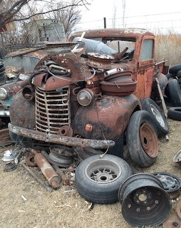 Rusty vintage truck in a scrapyard with old tires and metal parts