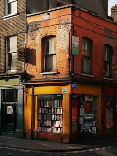 Yellow and burnt orange corner bookshop building with display windows on city street
