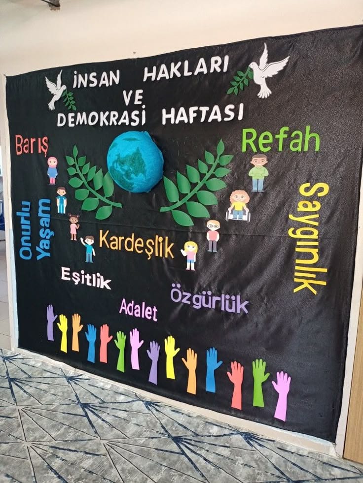 Dark bulletin board with Turkish text about human rights and democracy week, featuring colorful children figures and raised hands.