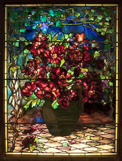 Stained glass window showing red roses in a vase with decorative floral border in Art Nouveau style