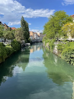 River canal in Ljubljana lined with trees and buildings under a blue sky
