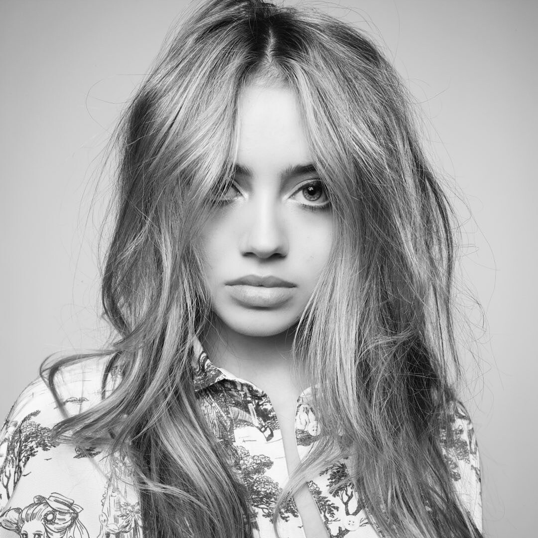 Black and white portrait of a young woman with mesy blonde hair and a patterned shirt