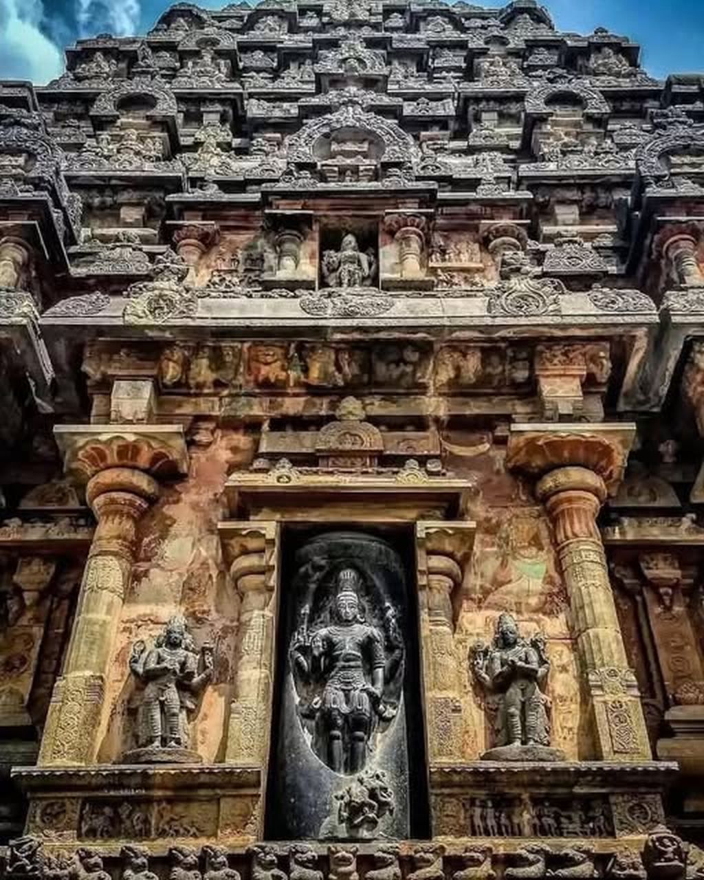 Ornately carved stone Hindu temple tower of Airavatesvara Temple in India under a clear sky.