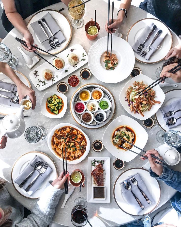 Overhead view of brunch spread with various dishes, drinks, and place settings on white table