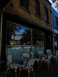 European-style café exterior in Sydney with wicker bistro chairs and tables on the sidewalk
