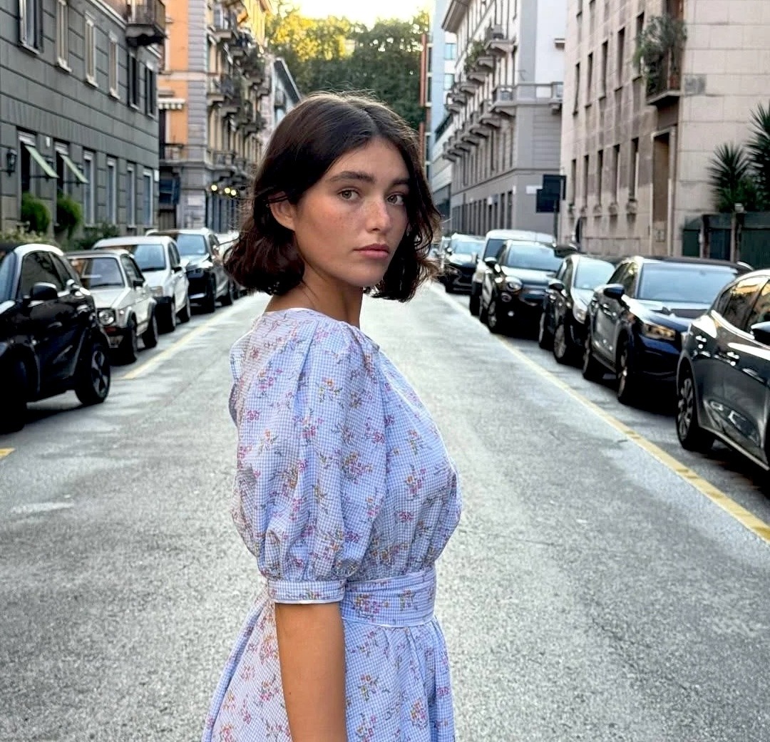 Young woman in a floral dress standing in the middle of a city street