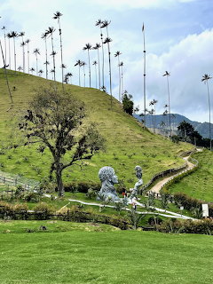 Tall wax palm trees on green hillsides in Cocora Valley, Colombia with sculptures in foreground